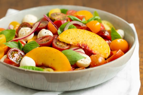 Tomato Peach Caprese Salad served in a grey bowl.