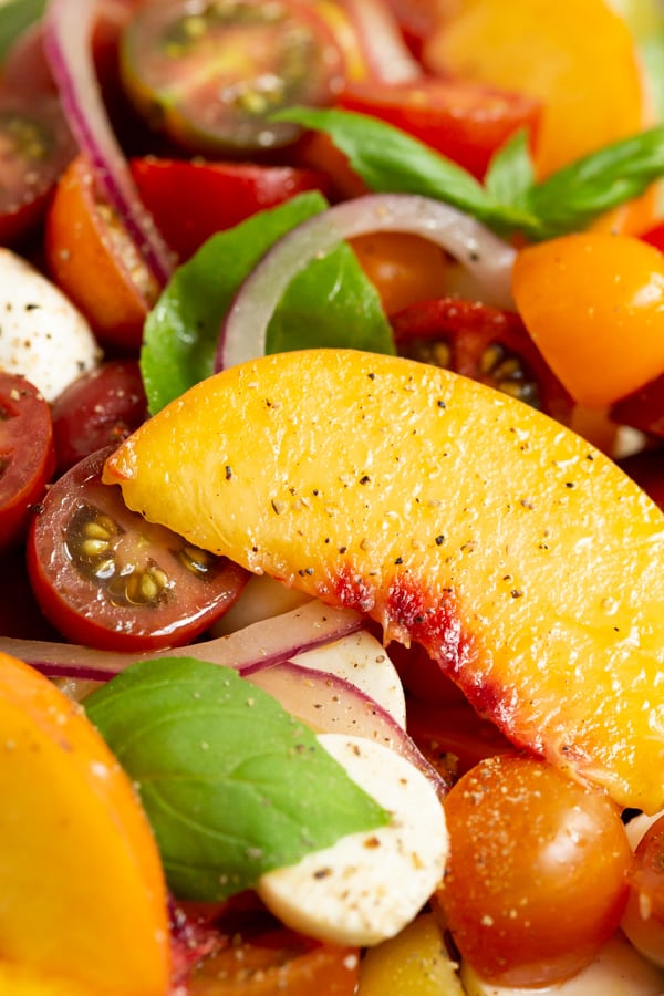 close up pictures of a sliced peach in a Tomato Peach Caprese Salad.