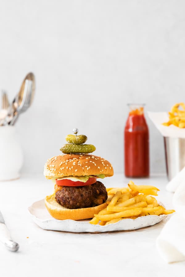 air fryer Juicy Lucy burger on a serving plate with french fries. 