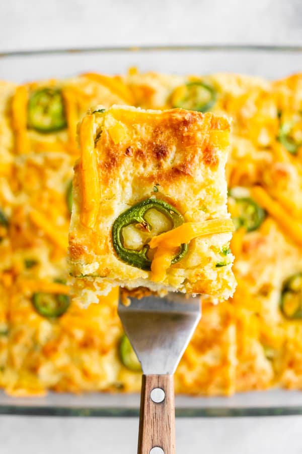 A piece of jalapeño cheddar cornbread on a spatula showing the jalapeno rings on the top of the cooked bread. 