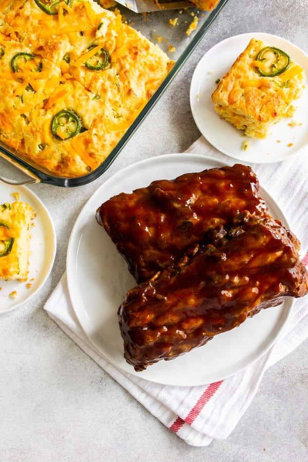 Jalapeño cheddar cornbread on plates served with bbq pork ribs. 