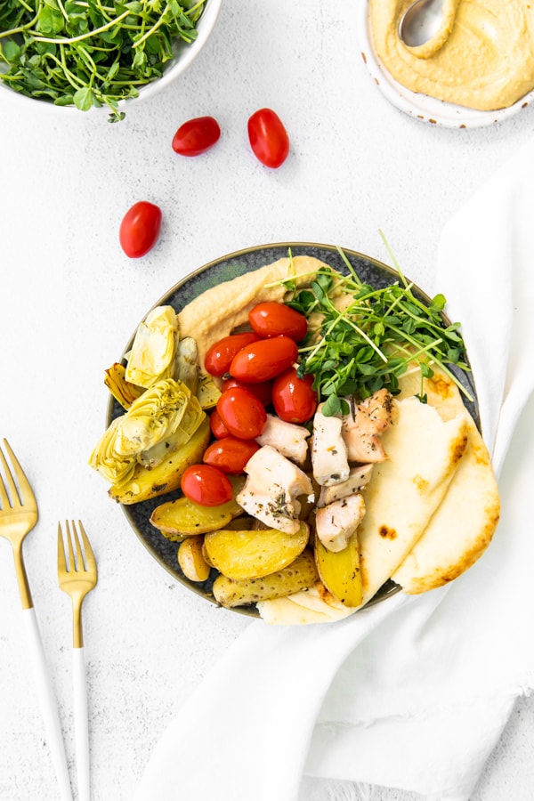 Sheet Pan Mediterranean Chicken plated with hummus and pita.