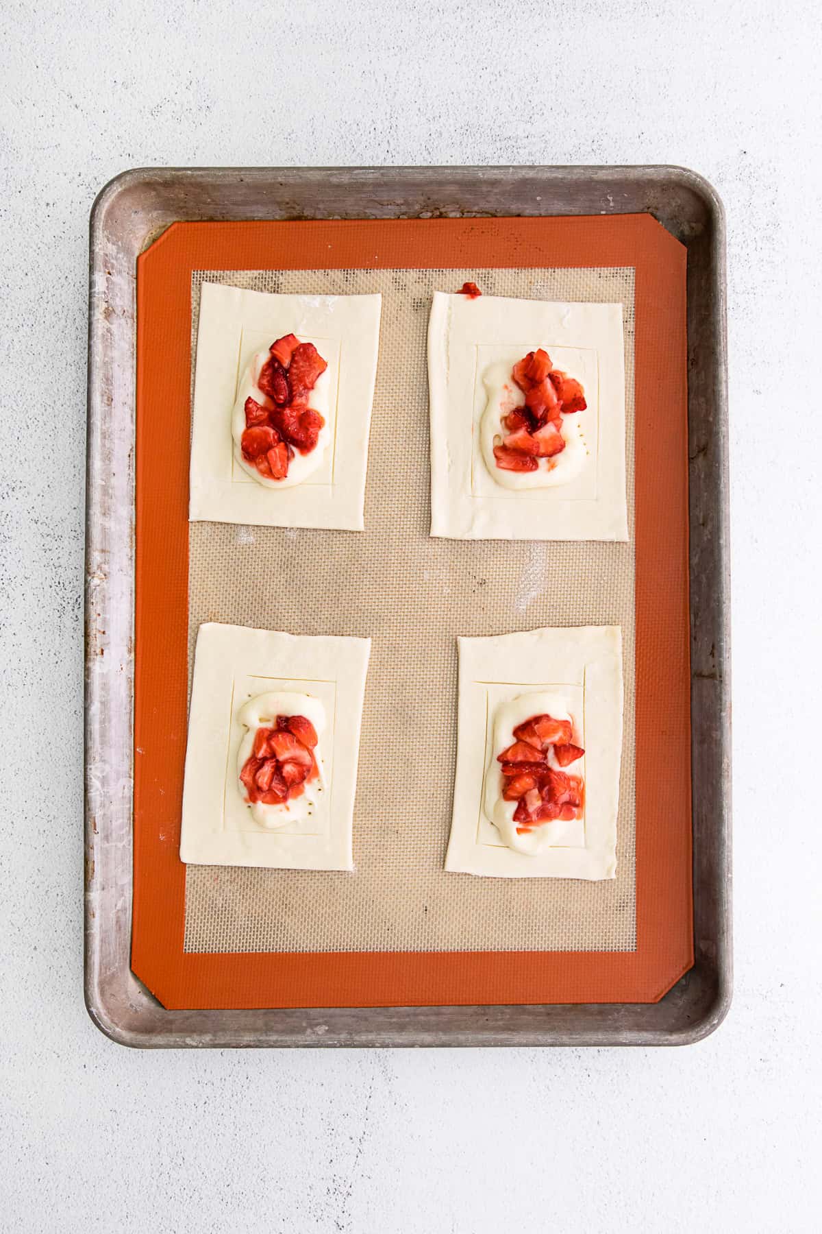 puff pastry with cheesecake and strawberries in the middle uncooked. 