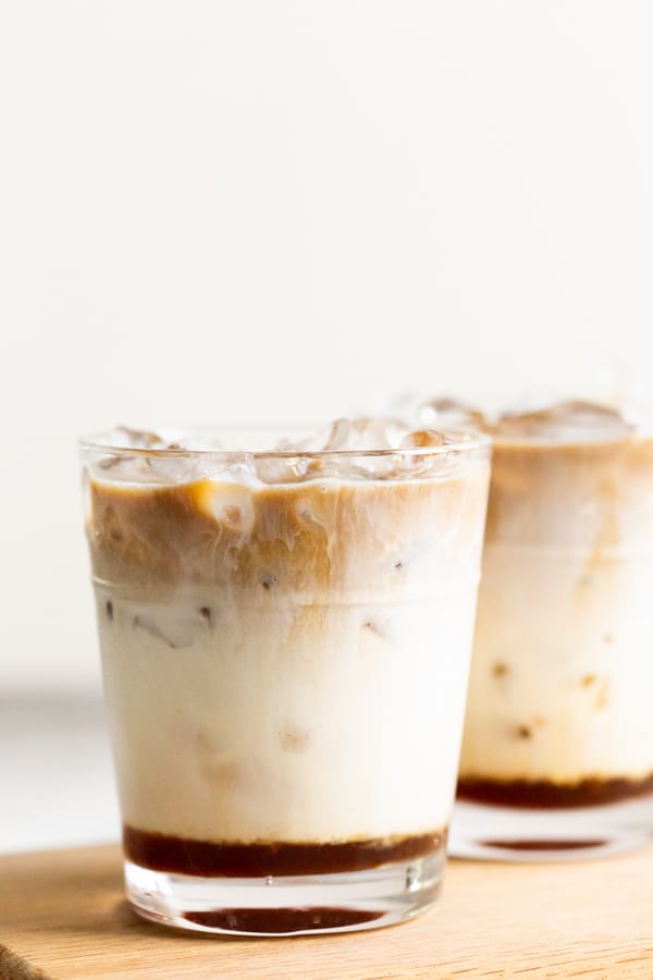 2 glasses of Apple Crisp Macchiato sitting on a cutting board. 