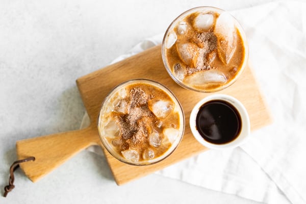 Apple Crisp Macchiato coffee drinks sitting on a mini wooden cutting board. 