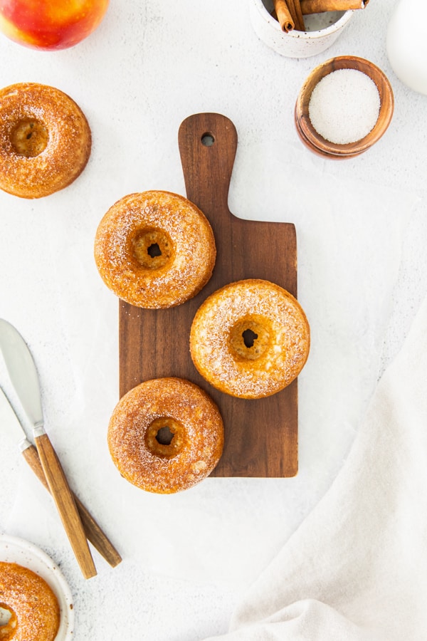 Baked apple cider donuts served on a wooden cutting board. 