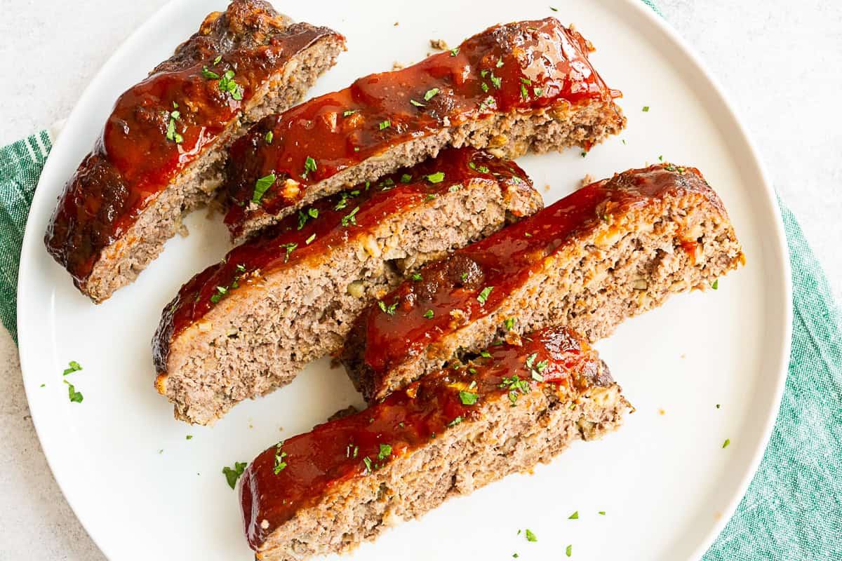 Classic Beef Meatloaf sliced on a white serving plate. 