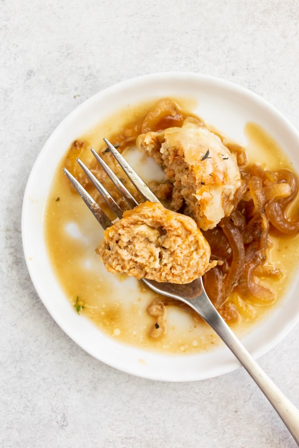 French Onion Chicken Meatball cut in half on a plate with a fork. 