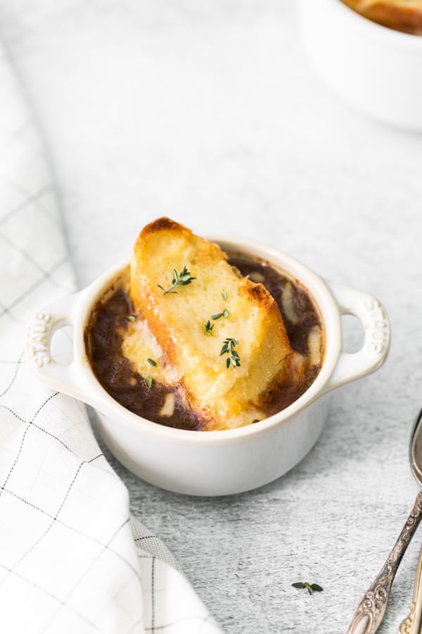 French Onion Soup in a soup bowl topped with a baguette and cheese. 