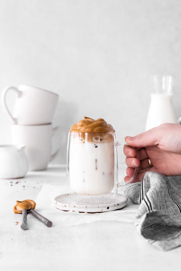 A hand holding a glass of Maple Whipped Coffee. 