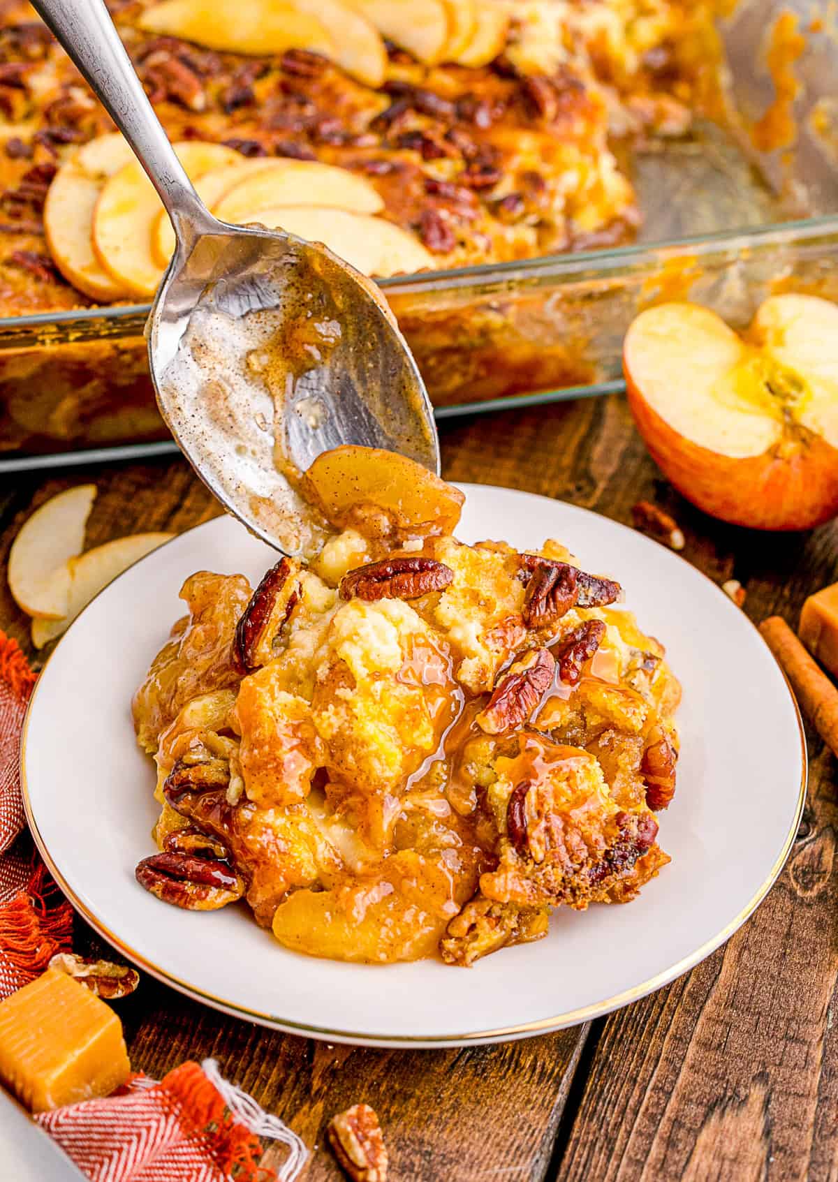 spooning Caramel Apple Dump Cake onto a plate. 