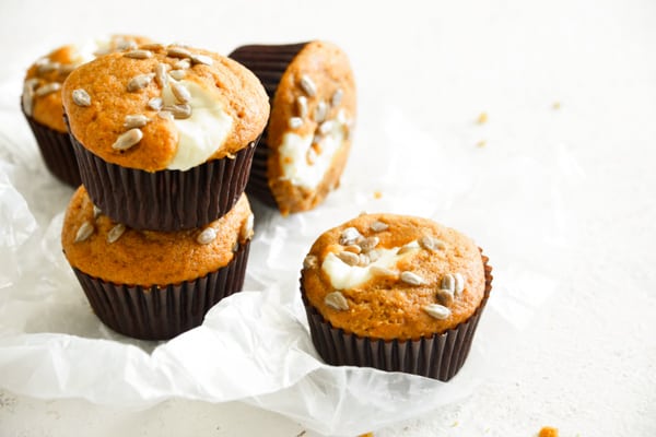 Pumpkin Cream Cheese Muffins stacked on a white board.