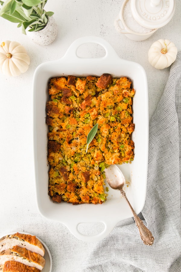 Sage and Cornbread Stuffing in a dish with a large scoop taken out. 