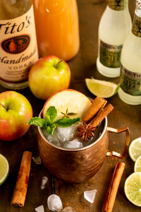 Apple Cider Moscow Mule on a table surrounded by ingredients.