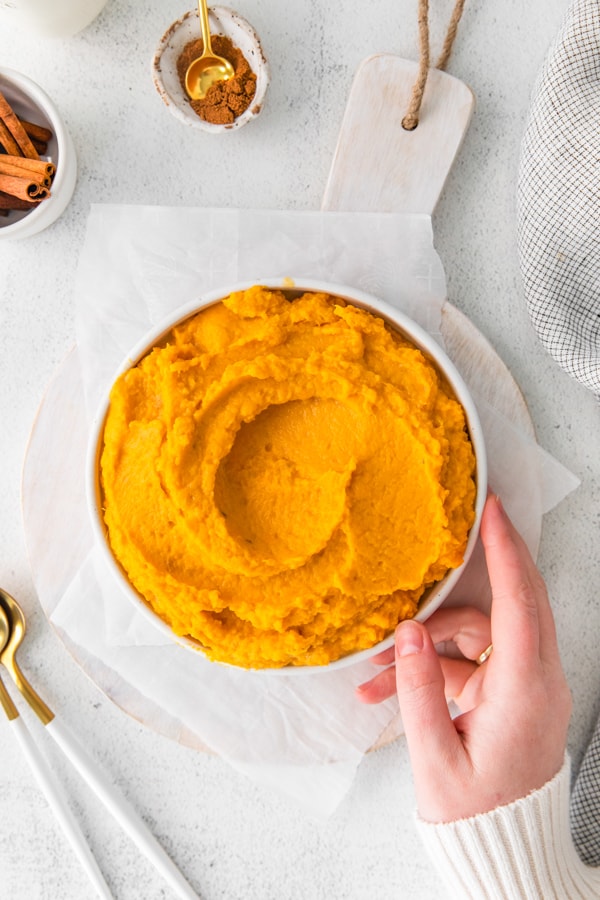 A hand holding the bowl of Instant Pot Mashed Sweet Potatoes. 