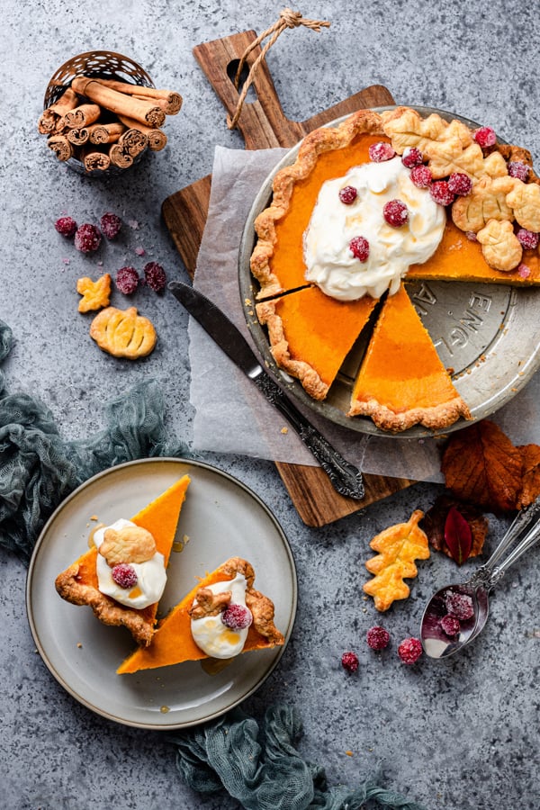 Pumpkin Cheesecake Pie served on a wooden cutting board with a slice on a plate.