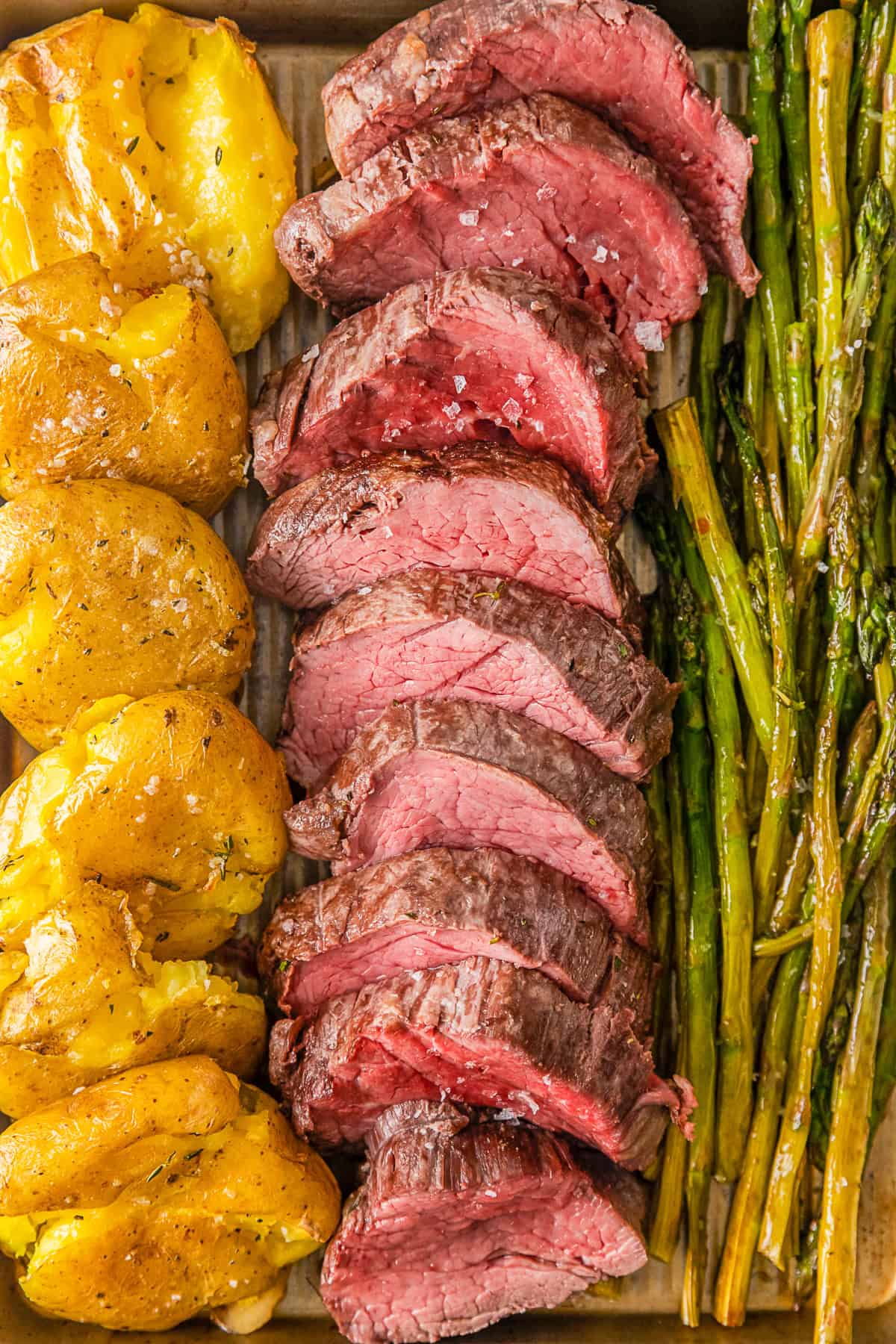Sheet pan Christmas dinner made with beef tenderloin, asparagus, and smashed potatoes. 
