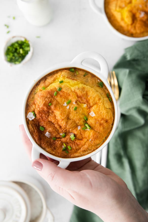A hand holding a ramekin of Air Fryer Frittata. 