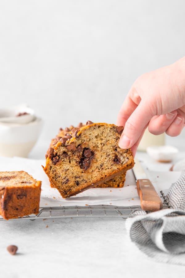 A hand grabbing a slice of Chocolate Chip Banana Bread. 