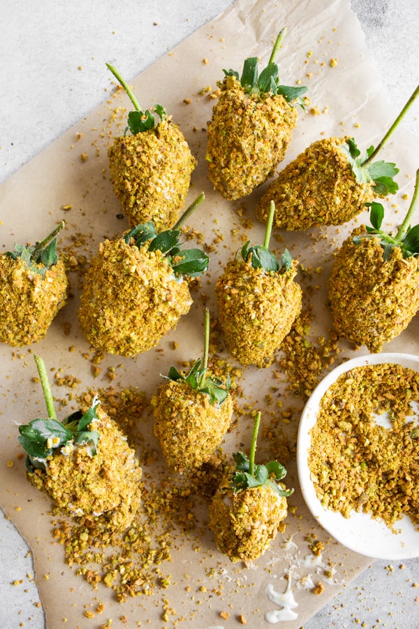 Pistachio White Chocolate Covered Strawberries sitting on parchment paper.