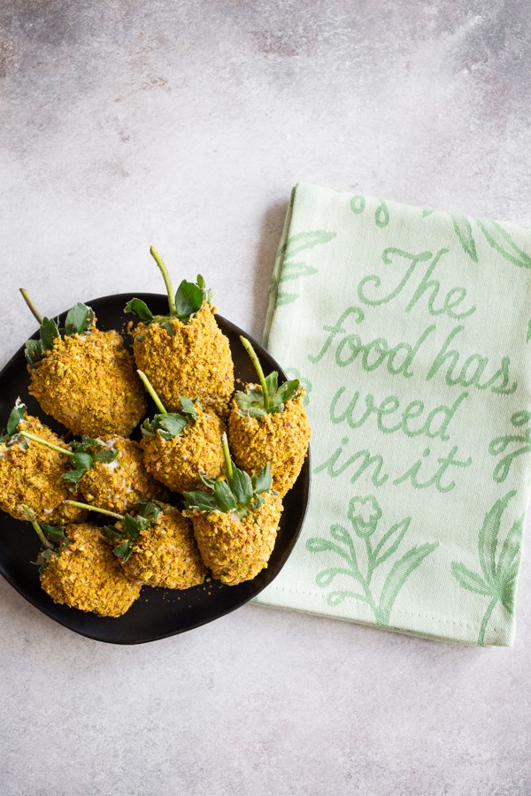Pistachio White Chocolate Covered Strawberries sitting on a board with a decorative towel.