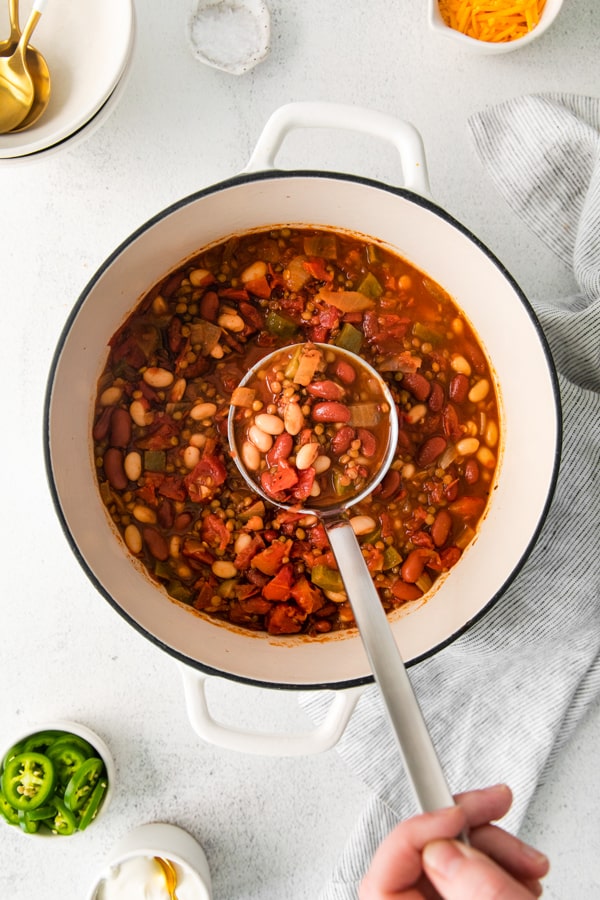 Vegan Lentil Chili being scooped out of a dutch oven soup pot.