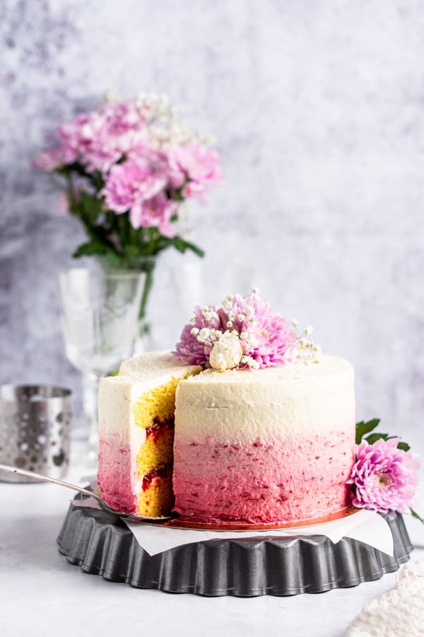  A piece being take out of a Strawberry Coconut Layer Cake. 