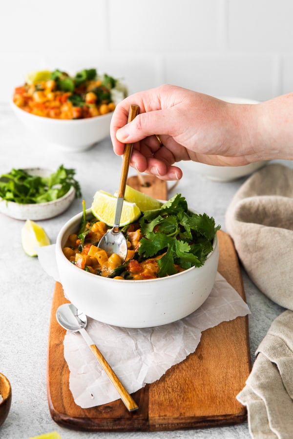 A hand taking a bite of Vegan Chickpea Curry out of the bowl.