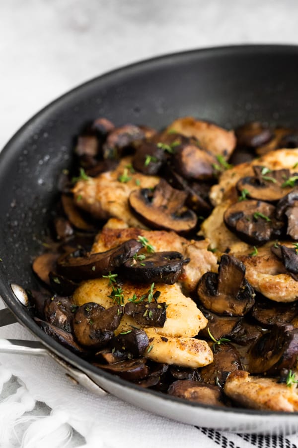 Garlic Mushroom Chicken Thighs in a pan sprinkled with fresh herbs.