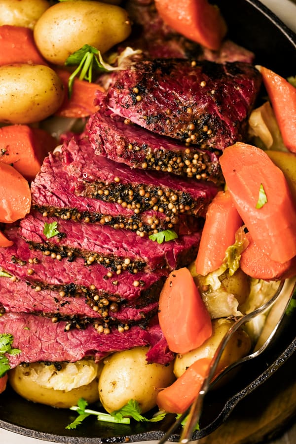 Sliced Instant Pot Corned Beef on a platter served with vegetables. 