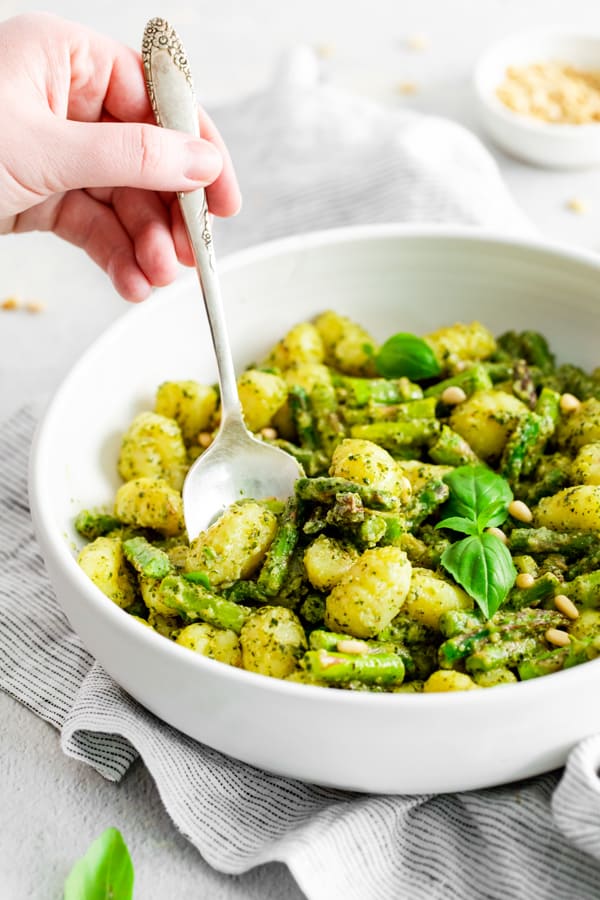 Pesto Gnocchi with Asparagus in a white bowl. 