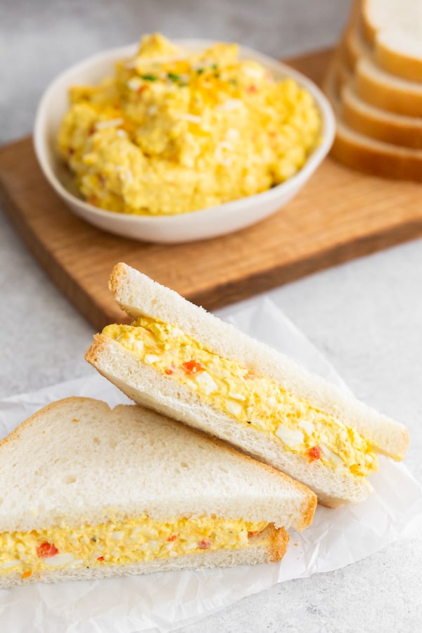 Pimento Cheese Egg Salad served on white bread and cut in half.