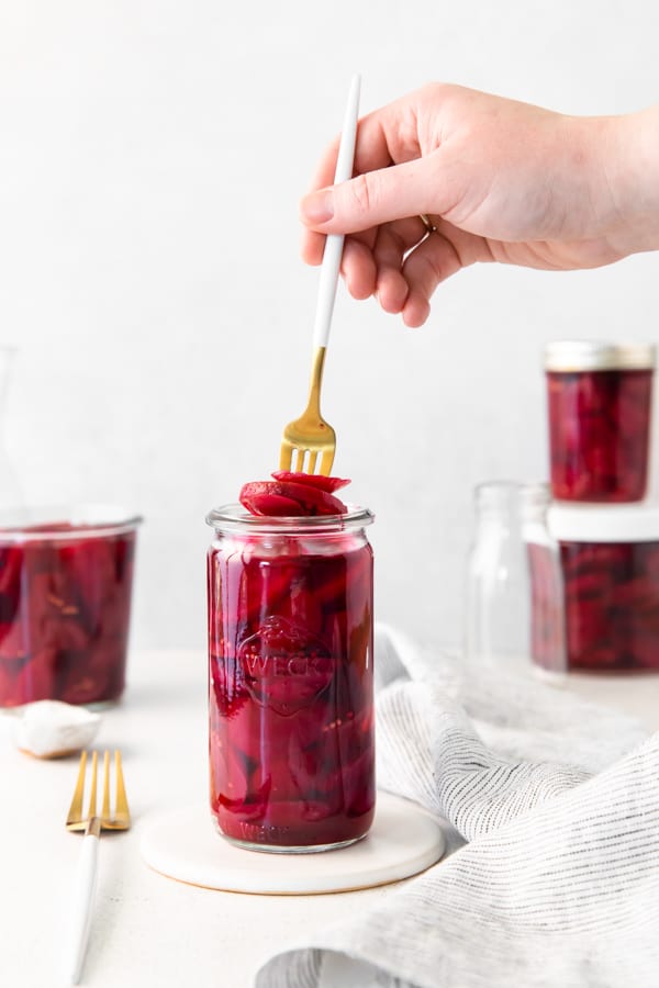 Hand holding a fork taking Quick Pickled Beets out of the jar.