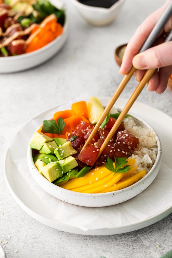 A chopstick grabbing a piece of poke tuna.