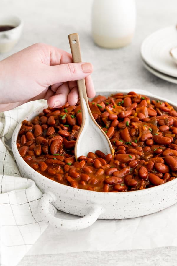 Scooping out Instant Pot Baked Beans out of a bowl. 