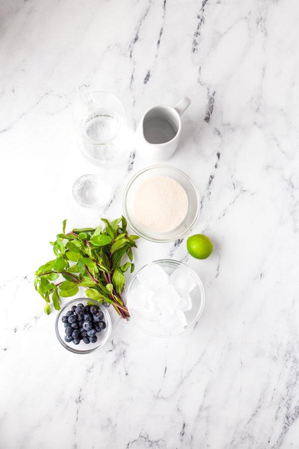 Ingredient to make a Blueberry Mojito sitting on a table. 