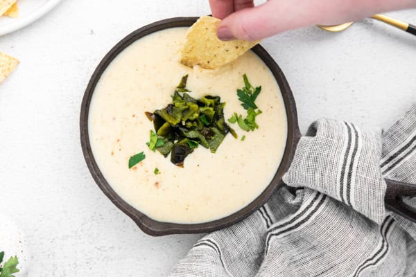A chip scooping up some white queso dip. 