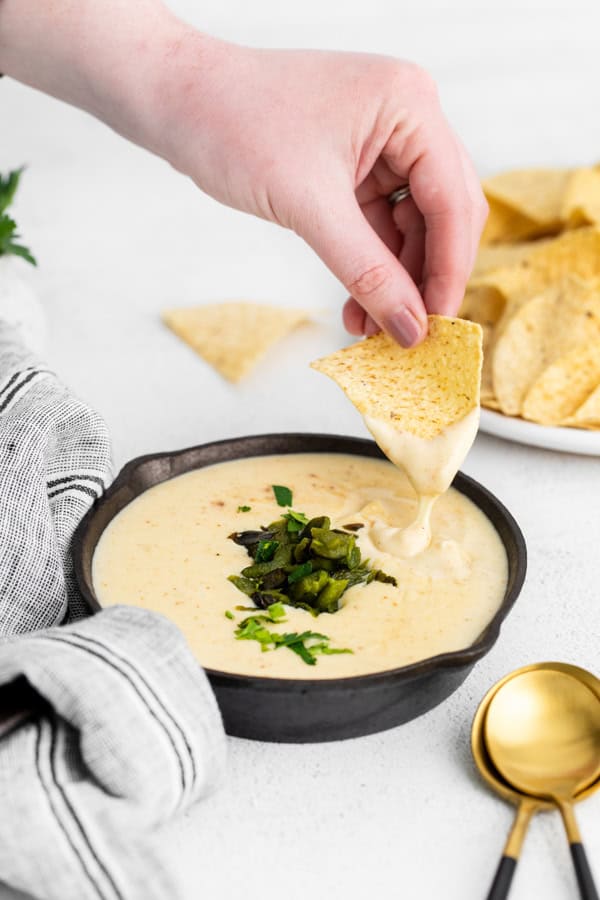 Roasted Poblano Queso getting scooped up with a chip. 