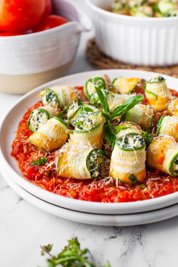 Zucchini Lasagna Rolls on a plate with extra red sauce. 