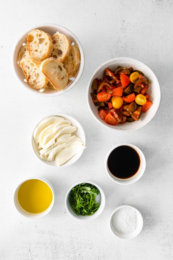 Ingredients to make Caprese Bruschetta sitting on a table. 