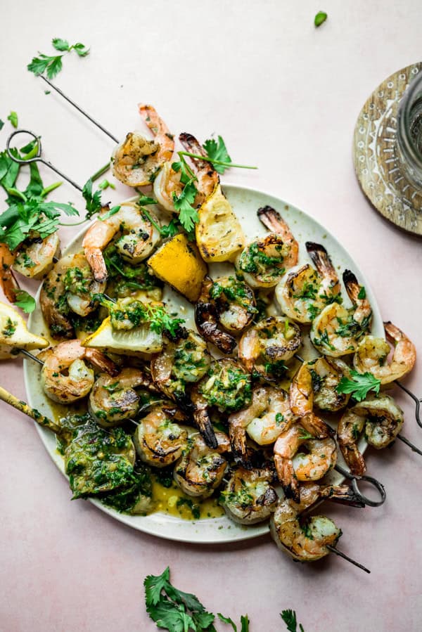 Chimichurri Grilled Shrimp Skewers served on a plate with lemons. 