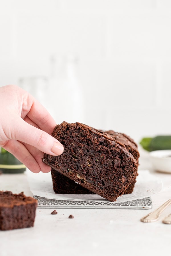 A hand holding a piece of Chocolate Zucchini Bread.