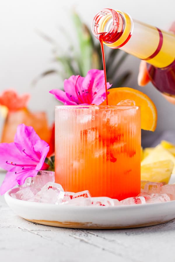 Pineapple Rum Punch having grenadine poured into the cocktail. 