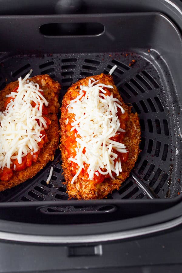 Crispy chicken cutlets in the air fryer topped with red sauce and cheese.