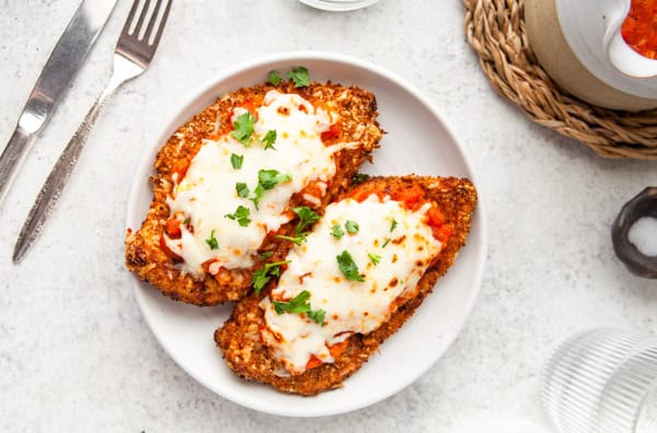 Air Fryer Chicken Parmesan sitting on a white plate.