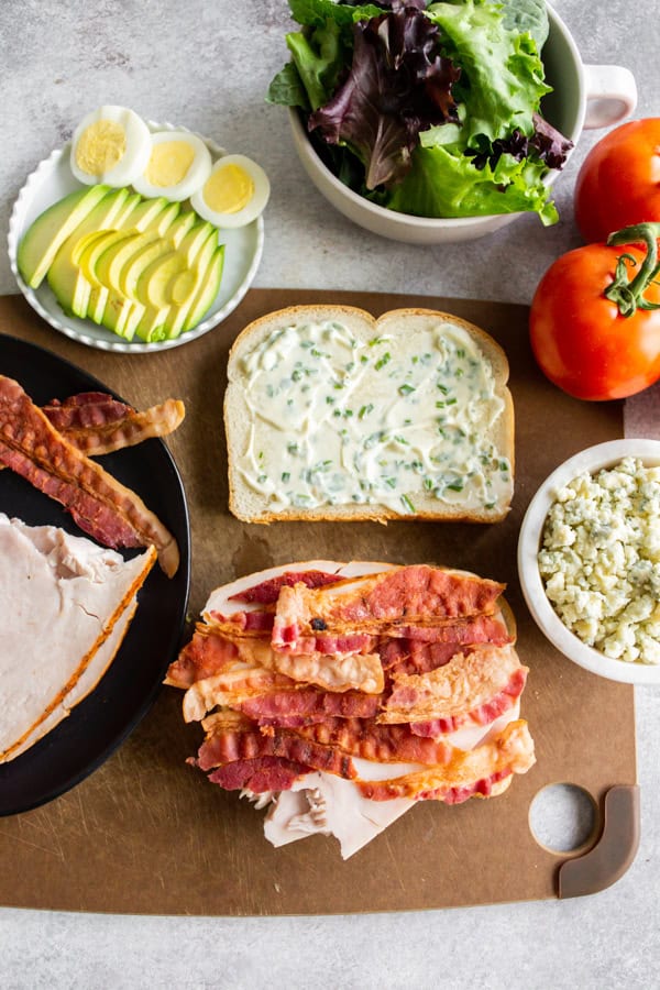 Cobb Salad Sandwich being made on a cutting board. 