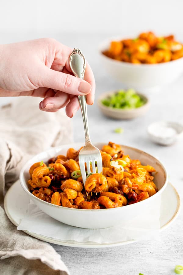 A fork going into a bowl of chili mac. 