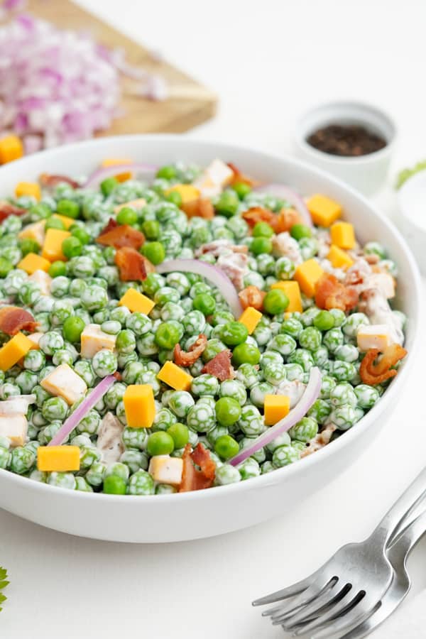 Classic Pea Salad in a bowl topped with extra bacon. 