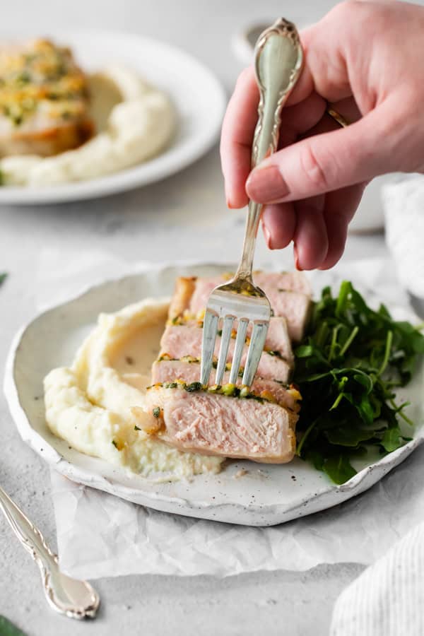 A fork picking up a slice of air fryer pork chop. 