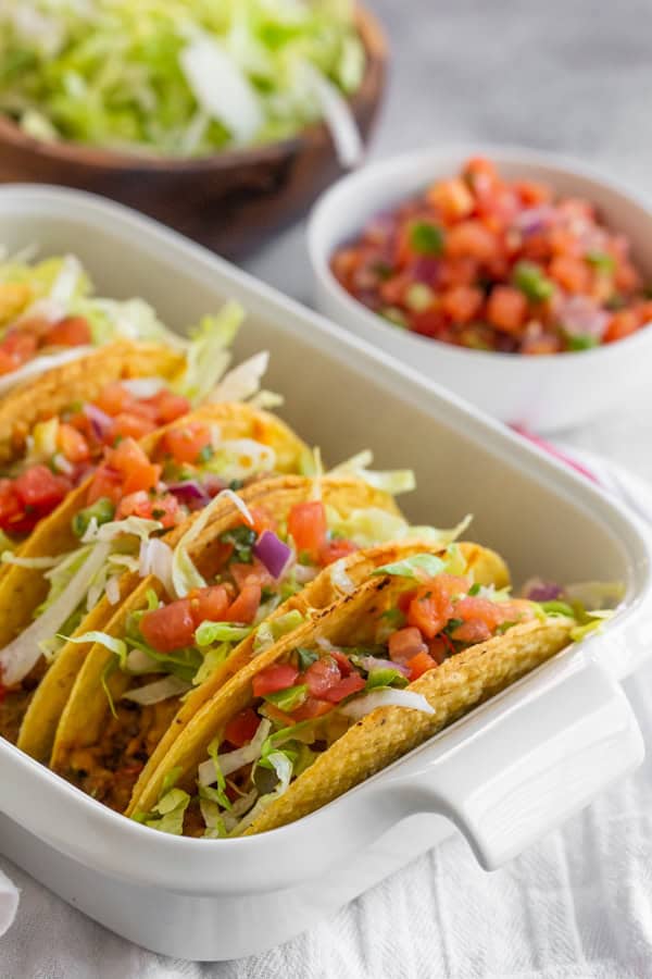 Baked Ground Beef Tacos topped with lettuce and tomatoes. 